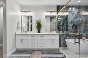 Full bath featuring a marble finish shower, double vanity, light wood finished floors, and a freestanding tub