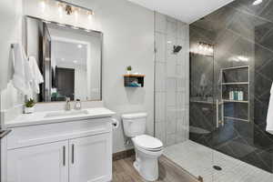 Bathroom with vanity, a marble finish shower, recessed lighting, and wood finished floors