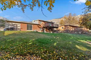 Back of house featuring brick siding, a yard, and a deck with mountain view