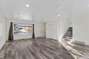 Living room with recessed lighting, wood finished floors, and stairs