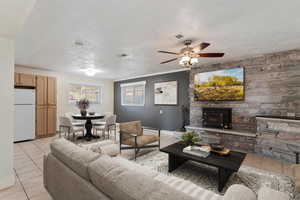 Living room featuring light tile patterned flooring, ornamental molding, ceiling fan, and a textured ceiling