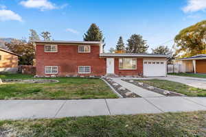 Tri-level home featuring brick siding, an attached garage, and concrete driveway