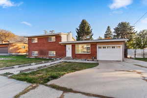 View of front of home with a garage, brick siding, and driveway
