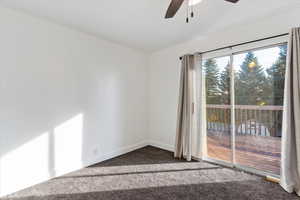 Unfurnished room with dark colored carpet and ceiling fan