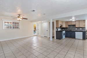 Kitchen with dark countertops, white appliances, open floor plan, backsplash, and a textured ceiling