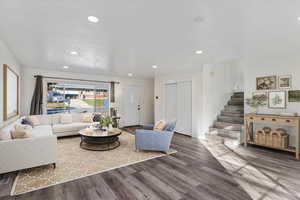 Living room with recessed lighting, wood finished floors, and stairs