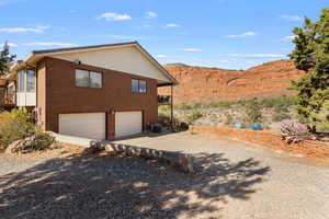 View of home's exterior with a balcony, brick siding, a garage, concrete driveway, and a mountain view