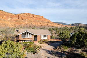 View of front of property with a chimney, a mountain view, driveway, and brick siding