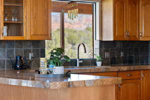 Kitchen featuring decorative backsplash, brown cabinetry, and tile countertops