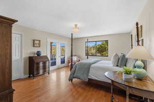 Bedroom featuring french doors, multiple windows, light wood finished floors, and access to outside