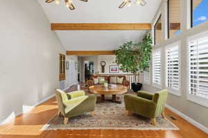 Living area featuring light wood-style floors, high vaulted ceiling, ceiling fan, and beam ceiling