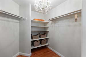 Walk in closet with dark wood-style floors and a chandelier