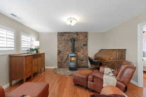 Living area featuring healthy amount of natural light, wood finished floors, and a wood stove