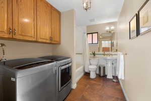 Laundry room featuring a chandelier, independent washer and dryer, and dark tile patterned floors