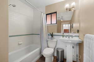 Bathroom featuring tile walls, shower / bathtub combination with curtain, dark tile patterned flooring, and a wainscoted wall