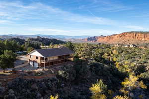 Aerial view of property and surrounding area featuring a mountain backdrop and a heavily wooded area
