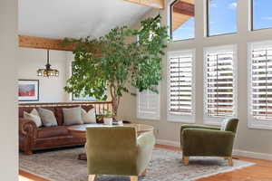 Living room with wood finished floors, beam ceiling, and high vaulted ceiling