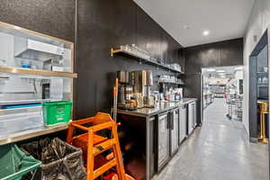 Kitchen featuring open shelves, stainless steel countertops, dark cabinets, and high quality fridge