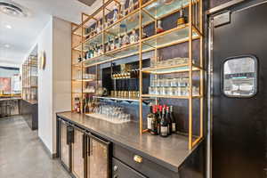 Indoor dry bar with stainless steel counters, wine cooler, and recessed lighting