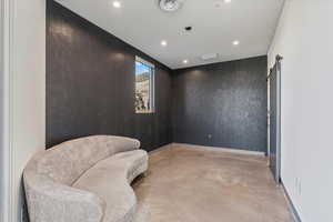 Sitting room featuring a barn door, finished concrete flooring, and recessed lighting
