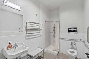 Full Employee bathroom with tile walls, a wainscoted wall, a stall shower.
