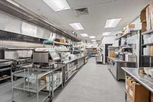 Kitchen with stainless steel countertops, a drop ceiling, and open shelves