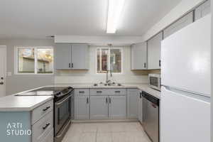 Kitchen featuring gray cabinets, appliances with stainless steel finishes, and light countertops