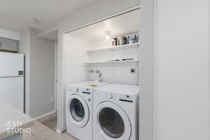 Laundry room featuring light tile patterned flooring and washer and clothes dryer