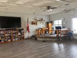 Living area featuring wood finished floors, a textured ceiling, and ceiling fan