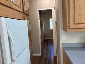 Kitchen featuring freestanding refrigerator, dark wood-type flooring, and brown cabinets