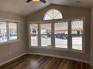 Unfurnished dining area featuring a textured ceiling, vaulted ceiling, dark wood-style floors, and a ceiling fan