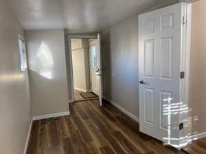 Unfurnished bedroom featuring dark wood-type flooring and a textured ceiling