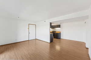 Unfurnished living room featuring light wood-style floors and baseboards