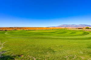 View of community with view of golf course, a yard, and a mountain view