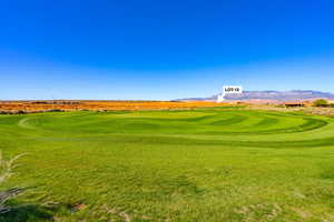 View of community with golf course view, a lawn, and a mountain view