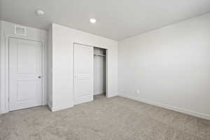 Unfurnished bedroom with light carpet, a closet, and a textured ceiling