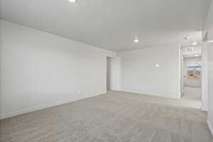 Unfurnished room with light carpet, recessed lighting, and a textured ceiling