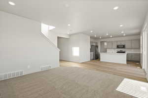 Unfurnished living room featuring recessed lighting, light colored carpet, and light wood-style flooring