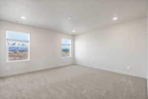 Carpeted spare room with baseboards and recessed lighting