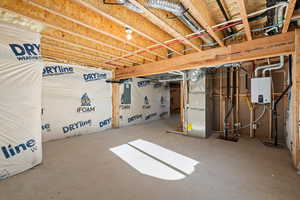 Unfinished below grade area featuring heating unit, water heater, drainage system, and electric panel