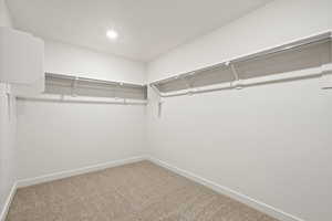 Walk in closet with light colored carpet