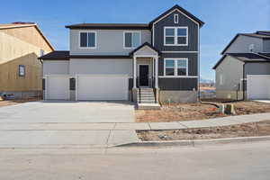 View of front of property with concrete driveway, an attached garage, and board and batten siding