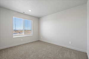 Carpeted spare room featuring baseboards and a textured ceiling