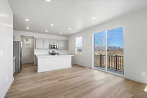 Kitchen featuring gray cabinets, recessed lighting, stainless steel appliances, a kitchen island with sink, and light wood finished floors