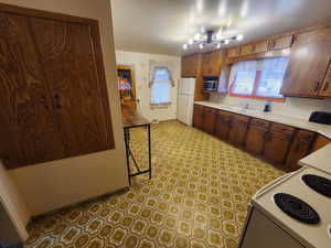 Kitchen with white appliances, light countertops, a chandelier, and healthy amount of natural light
