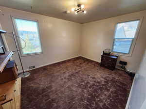 Unfurnished bedroom with dark carpet and baseboards