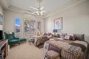 Carpeted bedroom featuring a raised ceiling and ceiling fan