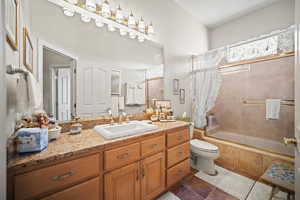 Full bathroom featuring vanity, tiled shower / bath combo, and dark tile patterned floors
