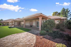 Back of house featuring a patio area, stucco siding, a tiled roof, and a lawn