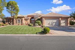 Mediterranean / spanish-style home with a front yard, a tile roof, driveway, stucco siding, and an attached garage